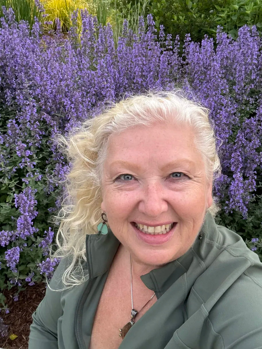 Janet smiling in front of purple flowers